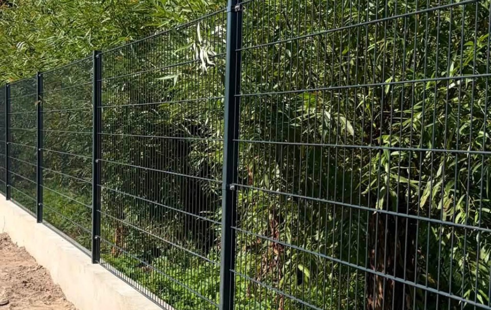 Ogrodzenie panelowe 3D z podmurówką betonową przy zielonym żywopłocie